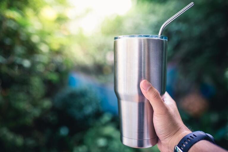 Handle a stainless steel tumbler/holds the temperature of cold or hot drinks with copy space Handle a stainless steel tumbler/holds the temperature of cold or hot drinks with copy space