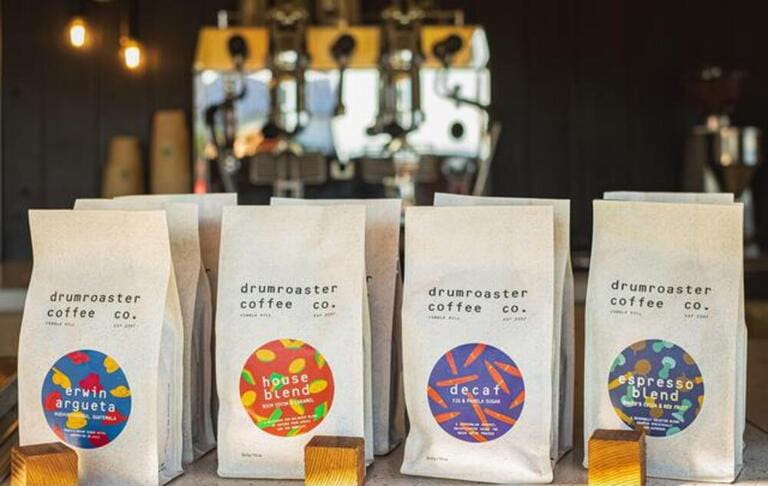 Various brand name coffee for sale in a coffee shop display. Various of coffee in paper bags.