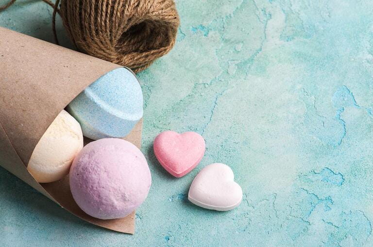 Blue, vanilla and strawberry bath bombs in the cone on turquoise concrete background