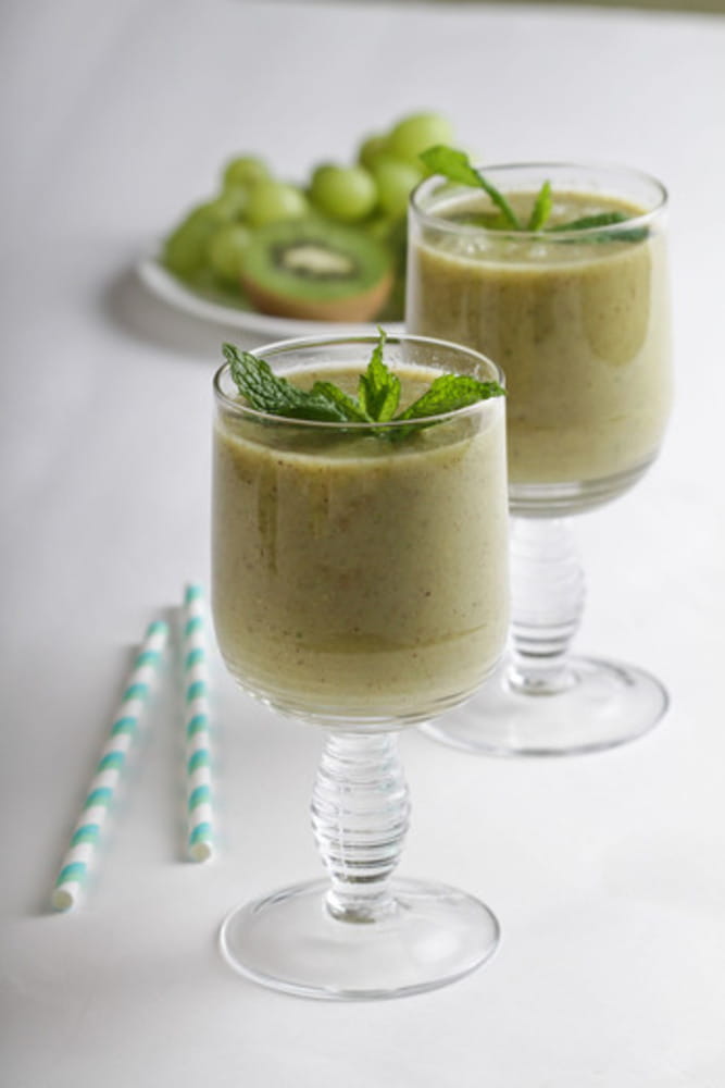 Two green smoothies with kiwis, green grapes, mint and honey.