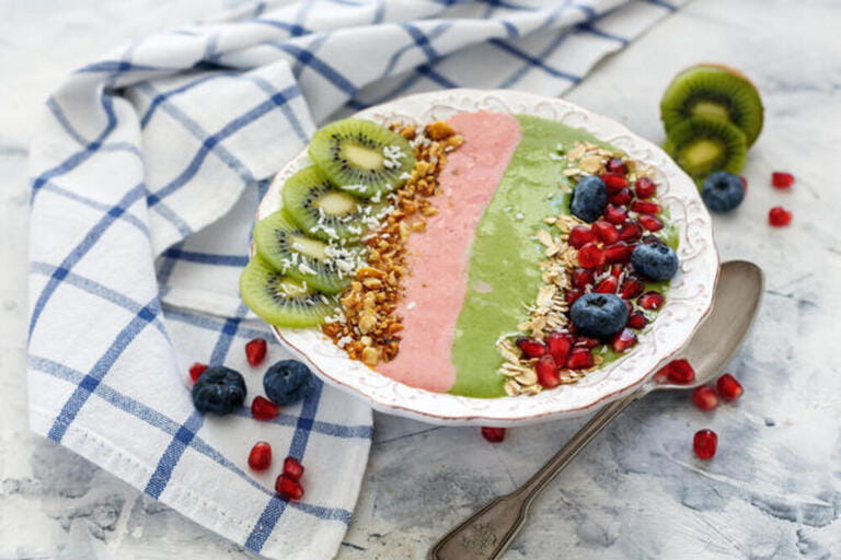 Smoothies bowl of spinach and strawberries with berries and fruit.