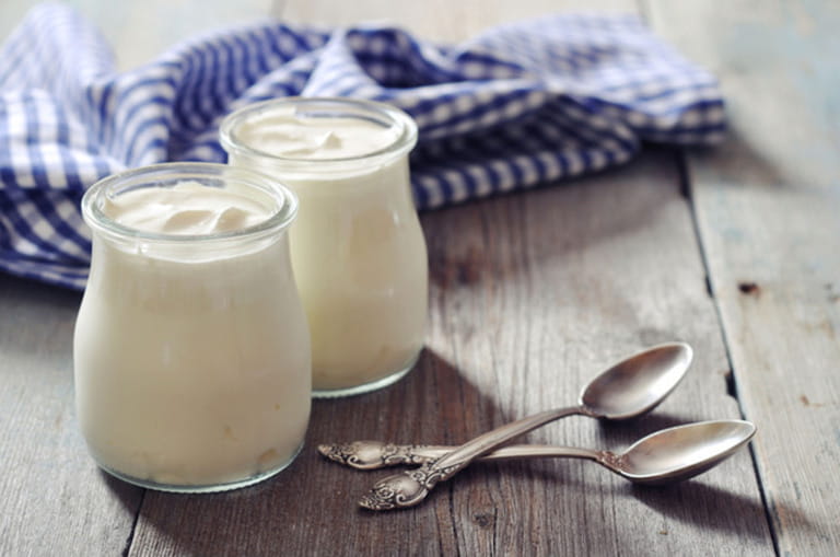 Greek yogurt in a glass jars with spoons on wooden background Greek yogurt in a glass jars with spoons on wooden background