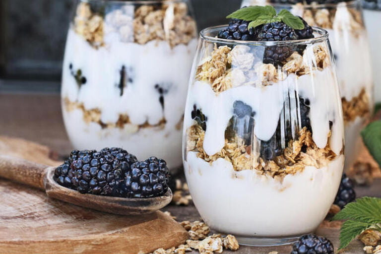 Blackberry parfaits made with Greek yogurt, granola and fresh blackberries. Extreme shallow depth of field with selective focus on parfait in foregrou Blackberry parfaits made with Greek yogurt, granola and fresh blackberries. Extreme shallow depth of field with selective focus on parfait in foregrou