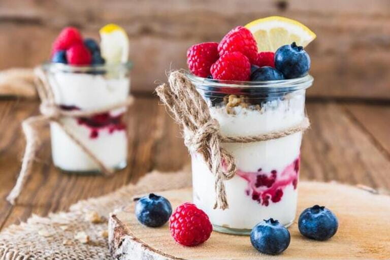 Yogurt with berries and cereals in a glass on a rustic wooden table Yogurt with berries and cereals in a glass on a rustic wooden table