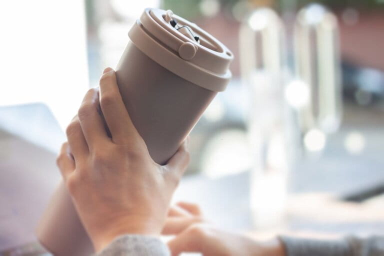 Woman holding a stainless steel thermos Woman holding a stainless steel thermos