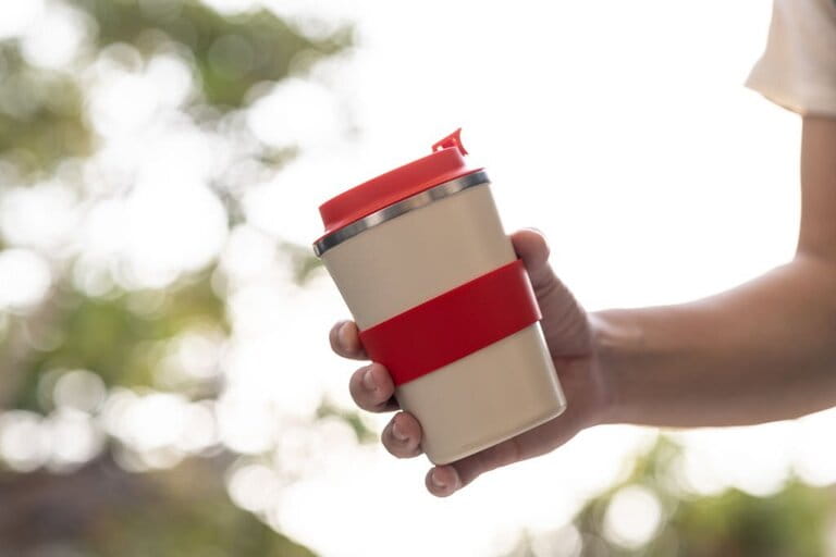 Close up hand with reusable drink storage with outdoor background. Concept for sustainability in day-to-day living Close up hand with reusable drink storage with outdoor background. Concept for sustainability in day-to-day living
