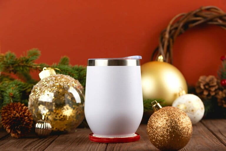 Christmas simulation of white thermos cup on wooden table with festive decorations. Christmas colors gold and red.
