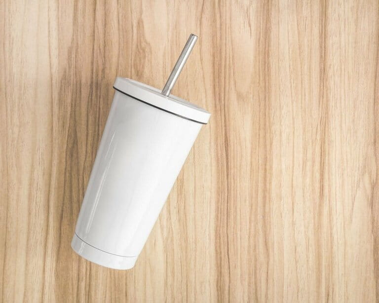 White steel cup with tube on wooden background. Insulated container to keep your drinks.