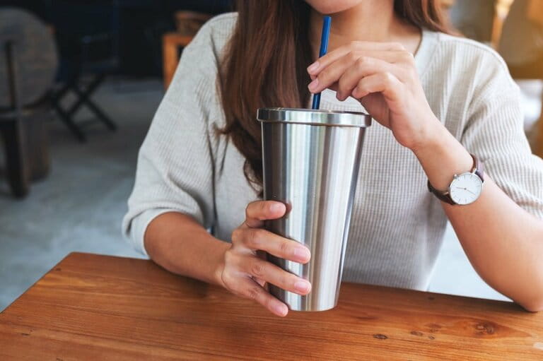 A woman drinks coffee in a stainless steel cup